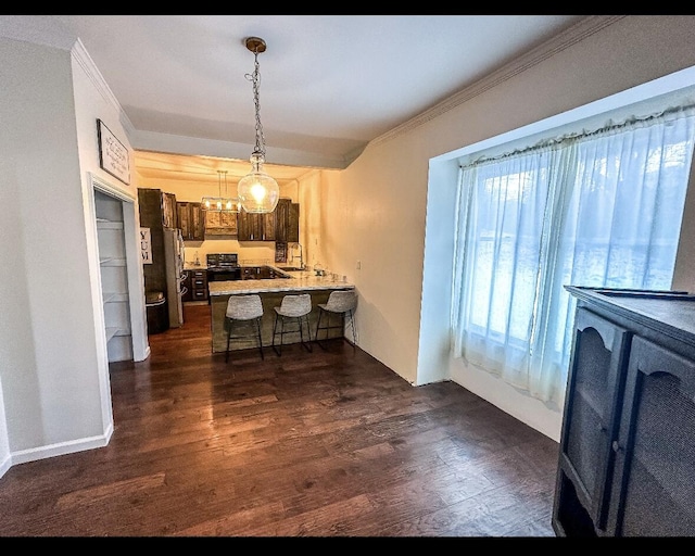 kitchen with kitchen peninsula, a kitchen bar, dark hardwood / wood-style flooring, dark brown cabinets, and stainless steel refrigerator