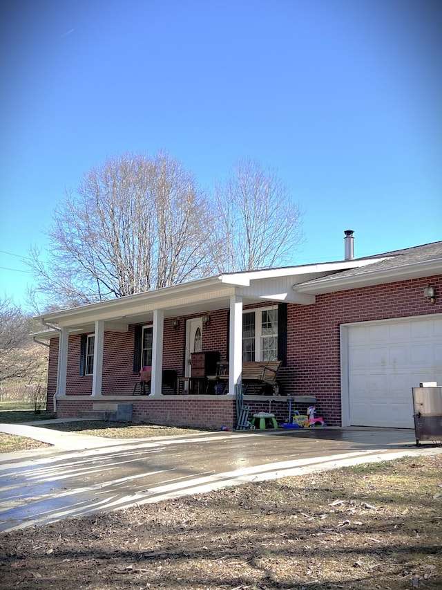 ranch-style home featuring a porch, an attached garage, brick siding, and concrete driveway