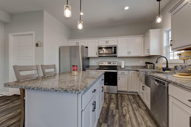 kitchen featuring a center island, a breakfast bar, hanging light fixtures, stainless steel appliances, and white cabinets