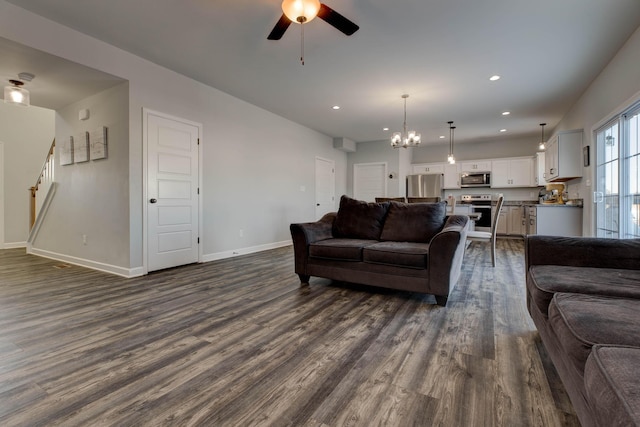 living room with ceiling fan with notable chandelier and dark hardwood / wood-style floors