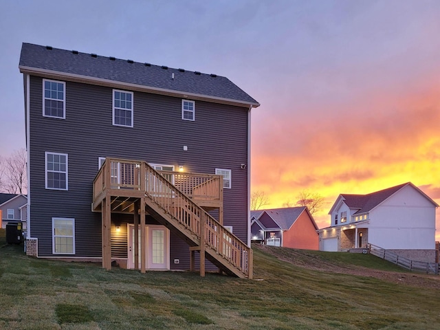 back house at dusk with a deck and a lawn