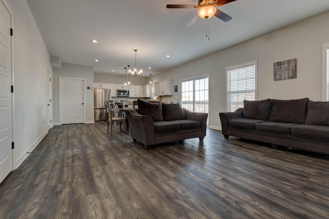 living room with dark wood-type flooring and ceiling fan with notable chandelier