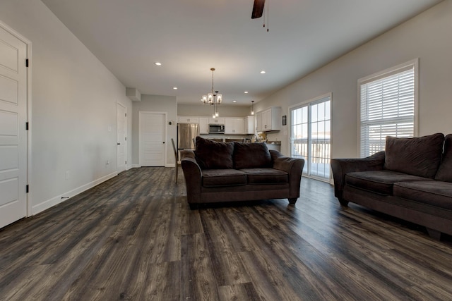 living room with dark hardwood / wood-style flooring and ceiling fan with notable chandelier