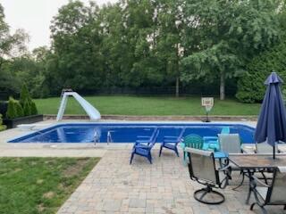 view of swimming pool with a lawn, a patio, and a water slide