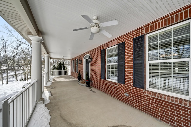 snow covered patio with ceiling fan and covered porch