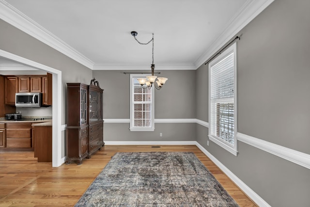 dining area featuring a chandelier, light hardwood / wood-style floors, and crown molding