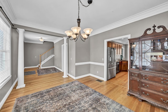 dining area featuring light wood-type flooring, ornamental molding, a wealth of natural light, and a chandelier