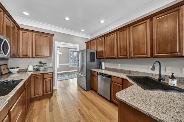 kitchen featuring sink, light stone counters, crown molding, light hardwood / wood-style floors, and appliances with stainless steel finishes