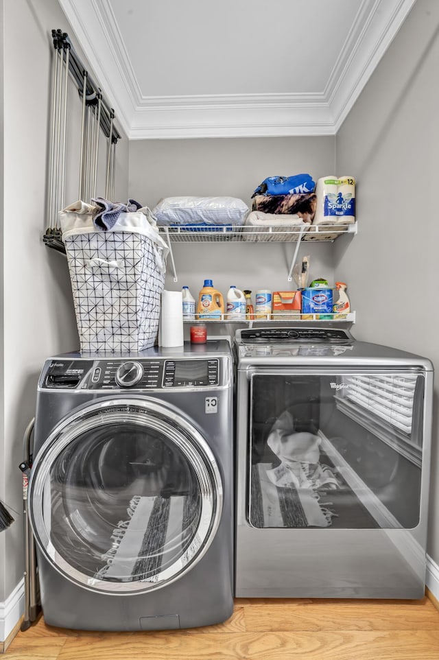 washroom featuring hardwood / wood-style flooring, crown molding, and washing machine and clothes dryer