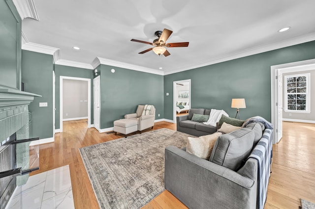 living room with ceiling fan, crown molding, light hardwood / wood-style floors, and a brick fireplace