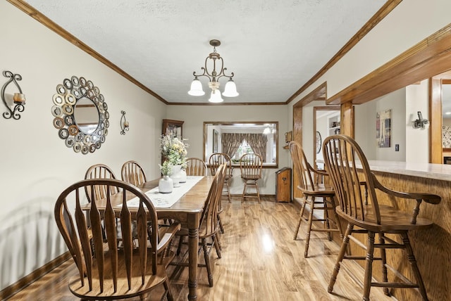 dining space with a notable chandelier, crown molding, a textured ceiling, and light hardwood / wood-style flooring