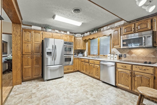 kitchen featuring a textured ceiling, backsplash, sink, and stainless steel appliances