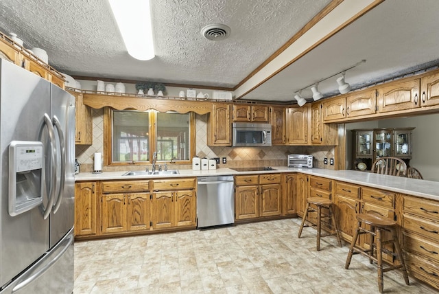 kitchen featuring sink, crown molding, a textured ceiling, decorative backsplash, and appliances with stainless steel finishes