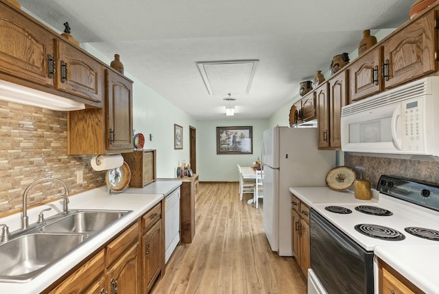 kitchen featuring white appliances, sink, light hardwood / wood-style flooring, decorative backsplash, and a textured ceiling