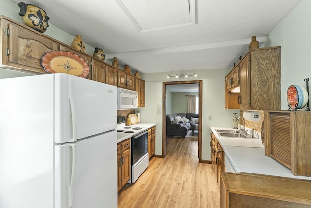 kitchen featuring light wood-type flooring, white appliances, and sink