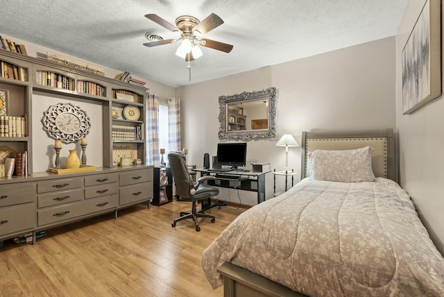 bedroom with ceiling fan, light hardwood / wood-style floors, and a textured ceiling