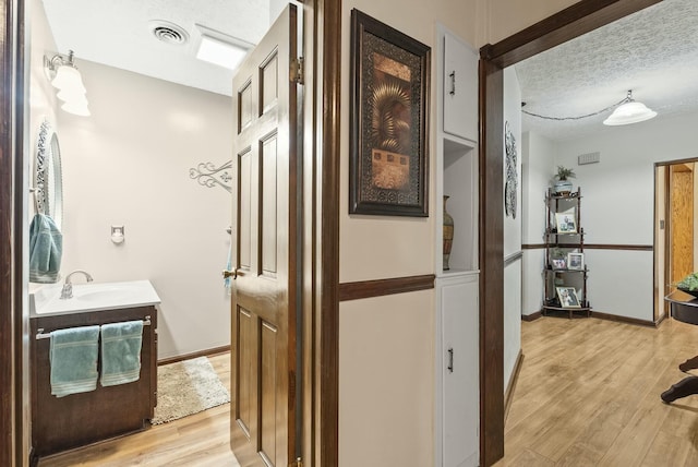 interior space with a textured ceiling, light wood-type flooring, and sink