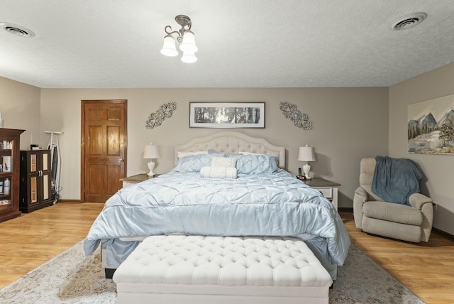 bedroom featuring a textured ceiling and light hardwood / wood-style flooring