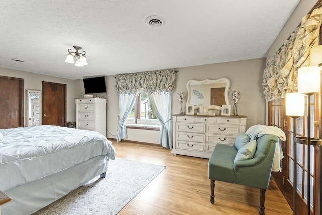 bedroom featuring light hardwood / wood-style floors and a textured ceiling