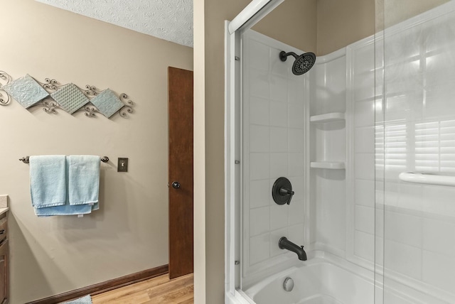 bathroom with hardwood / wood-style flooring, vanity, bath / shower combo with glass door, and a textured ceiling