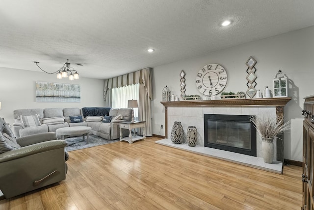 living room featuring a fireplace, wood-type flooring, a textured ceiling, and a notable chandelier