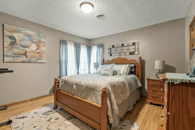 bedroom featuring light hardwood / wood-style floors and a textured ceiling