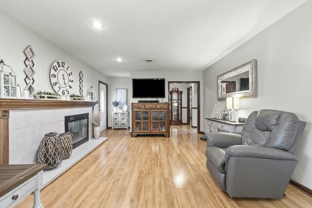 living room with a tile fireplace and light hardwood / wood-style flooring