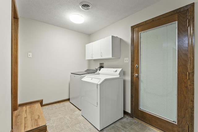 laundry room featuring washer and clothes dryer, cabinets, and a textured ceiling