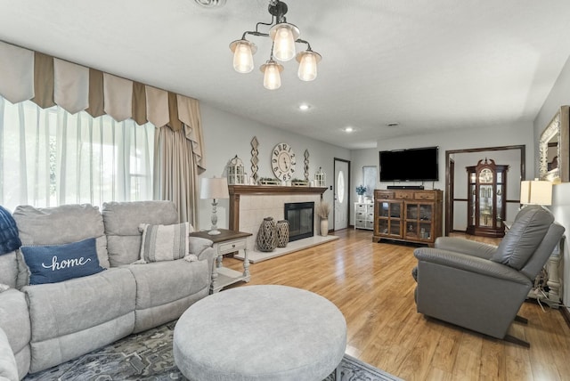 living room featuring a notable chandelier, wood-type flooring, and a fireplace