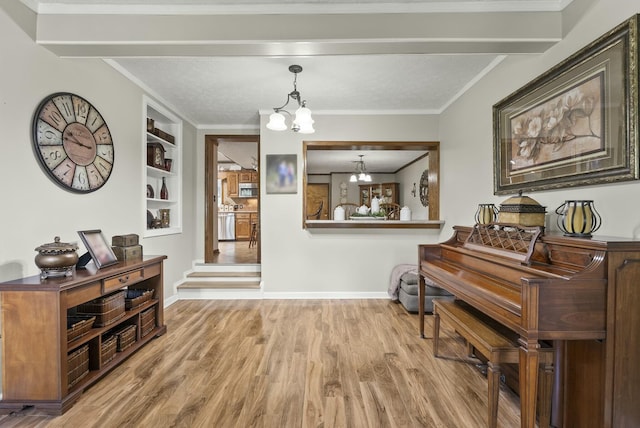 miscellaneous room with built in shelves, crown molding, beam ceiling, a notable chandelier, and light hardwood / wood-style floors