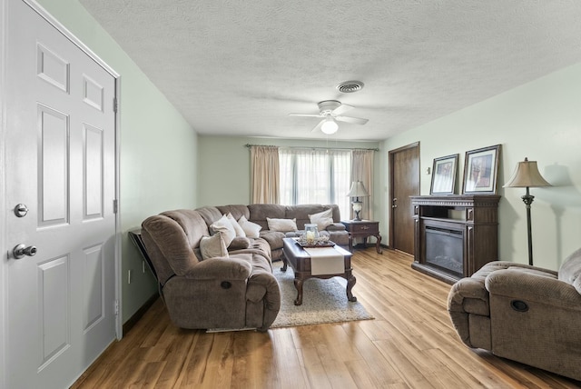 living room featuring a textured ceiling, light hardwood / wood-style floors, and ceiling fan