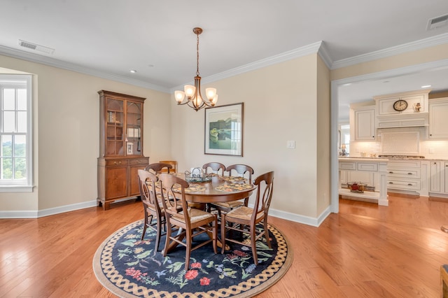 dining area featuring light hardwood / wood-style floors, crown molding, and a chandelier