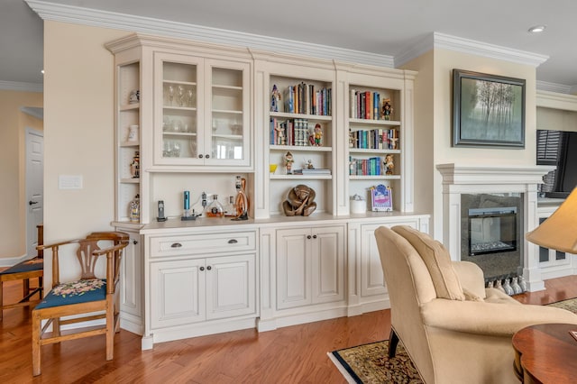 living area featuring a fireplace, light hardwood / wood-style flooring, and ornamental molding