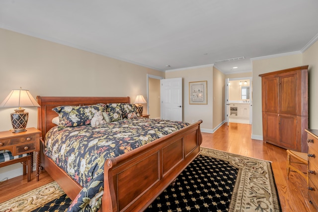 bedroom featuring light wood-type flooring, ornamental molding, and ensuite bath