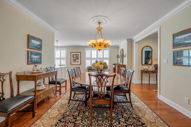 dining area featuring light wood-type flooring, an inviting chandelier, and crown molding