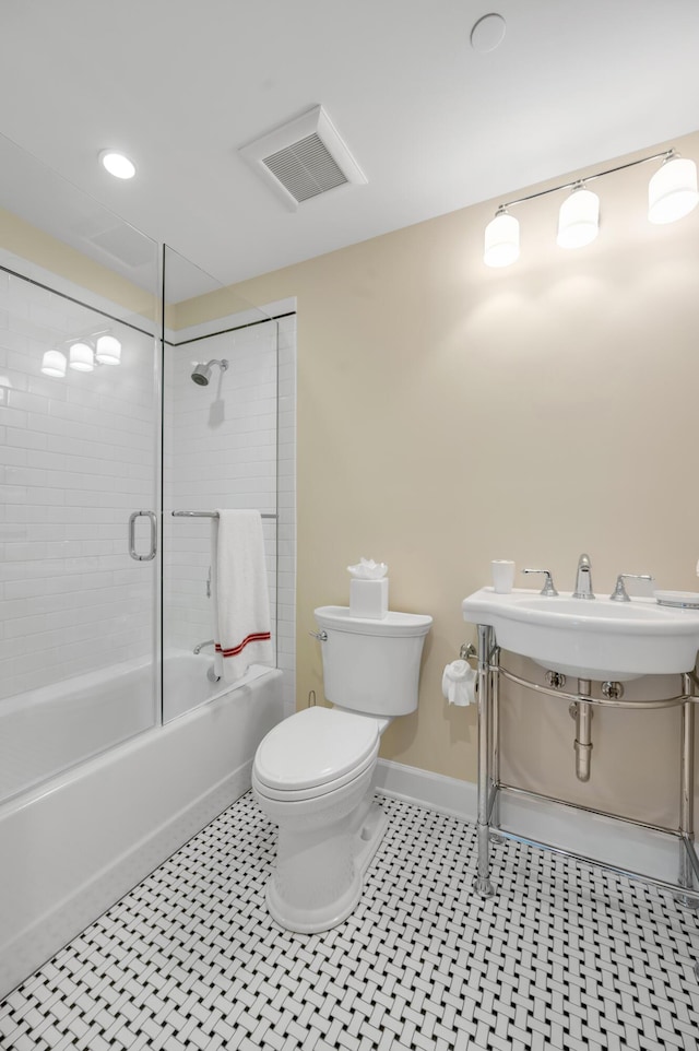 bathroom featuring tile patterned flooring, toilet, and tiled shower / bath