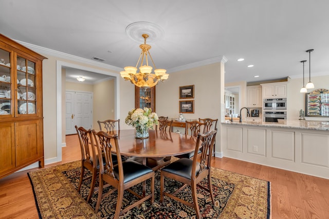 dining space with light hardwood / wood-style floors, crown molding, and a notable chandelier