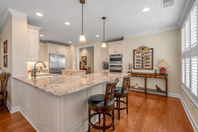 kitchen featuring kitchen peninsula, appliances with stainless steel finishes, tasteful backsplash, a healthy amount of sunlight, and decorative light fixtures