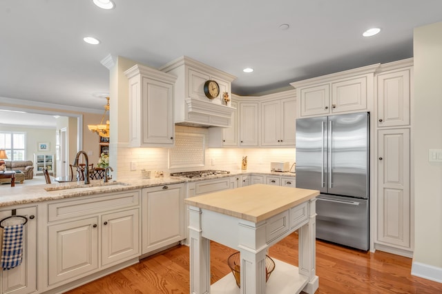 kitchen featuring hanging light fixtures, sink, light hardwood / wood-style flooring, and appliances with stainless steel finishes