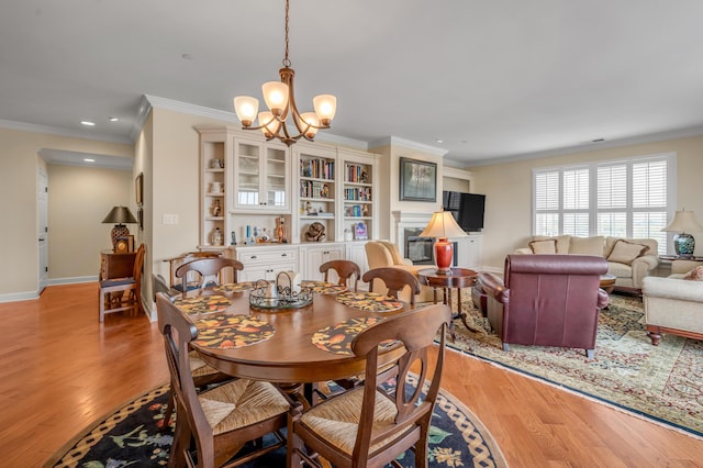 dining room with light wood-type flooring, an inviting chandelier, and crown molding