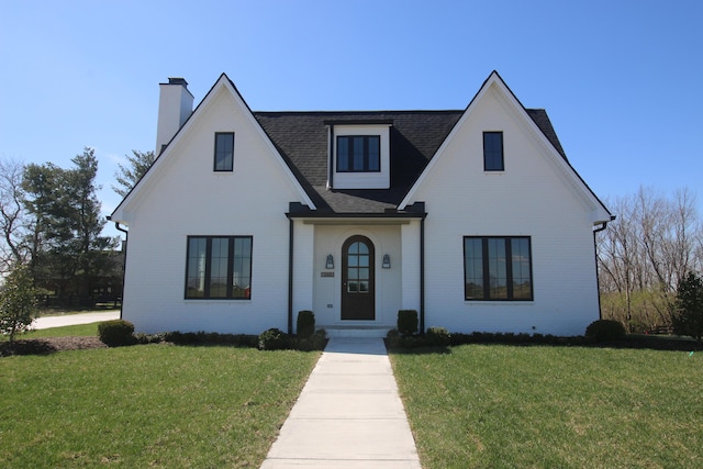 view of front of home featuring brick siding, a shingled roof, and a front lawn