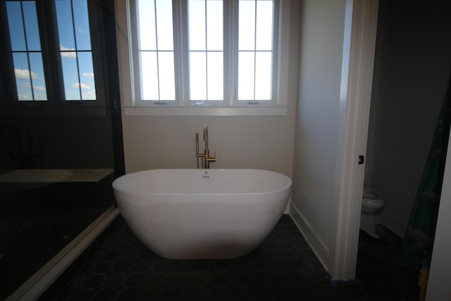 full bathroom featuring baseboards, toilet, and a freestanding tub