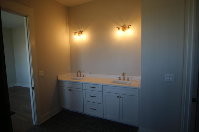 bathroom with baseboards, double vanity, and a sink