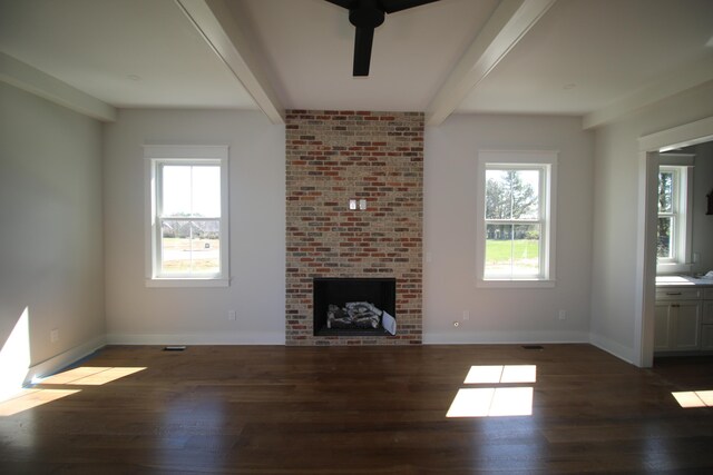 unfurnished living room with a brick fireplace, beam ceiling, and dark hardwood / wood-style flooring