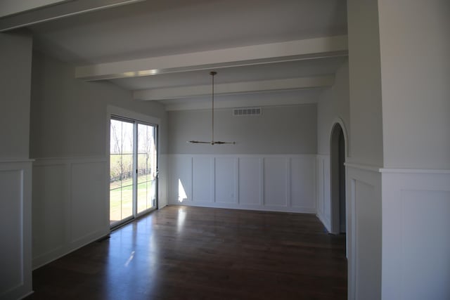 unfurnished dining area with a wainscoted wall, arched walkways, dark wood-style floors, beamed ceiling, and visible vents