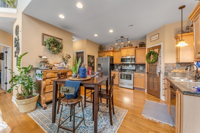 kitchen featuring stainless steel appliances, tasteful backsplash, sink, hanging light fixtures, and light hardwood / wood-style flooring