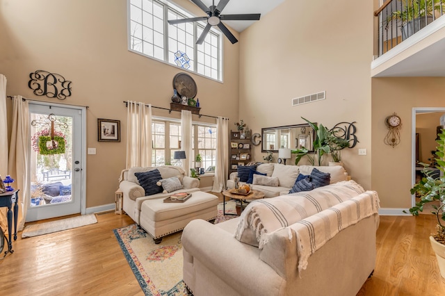 living room with plenty of natural light, a towering ceiling, and light wood-type flooring