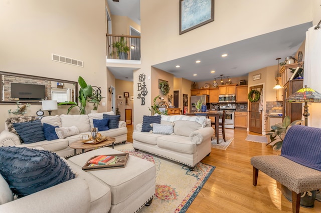 living room featuring a towering ceiling and light hardwood / wood-style floors