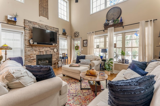 living room featuring a high ceiling, a wealth of natural light, hardwood / wood-style floors, and a fireplace