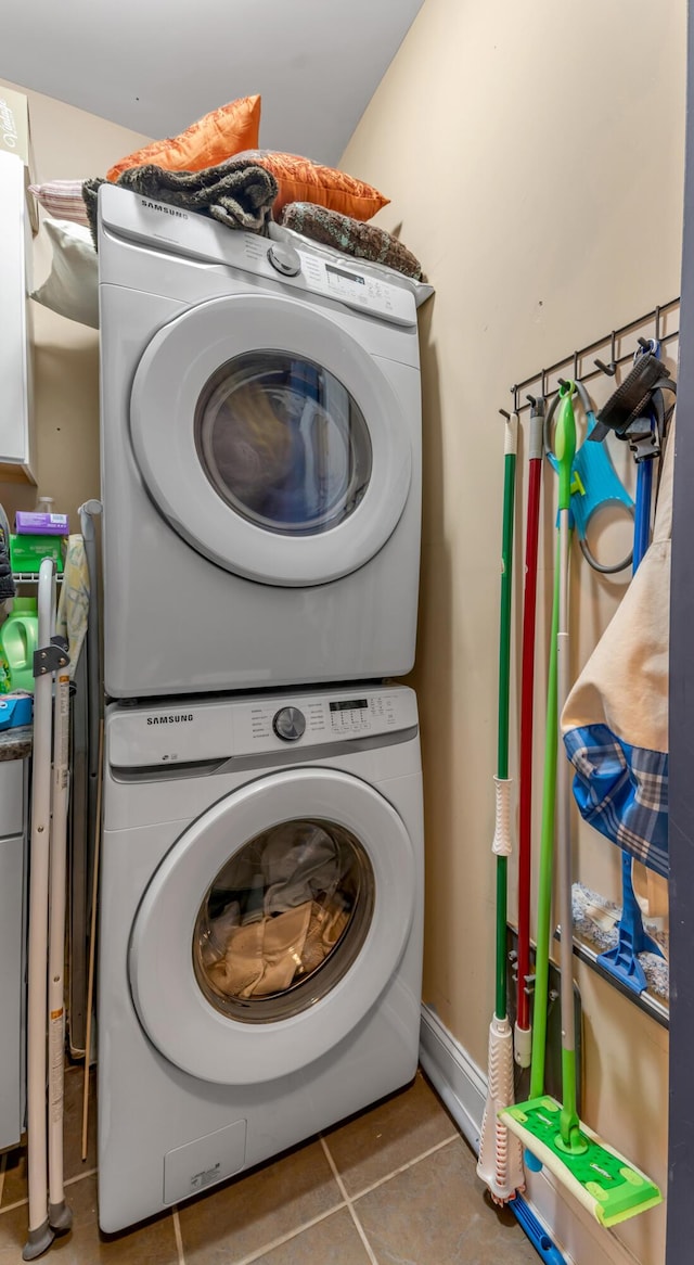 laundry room featuring stacked washer and dryer and tile patterned flooring